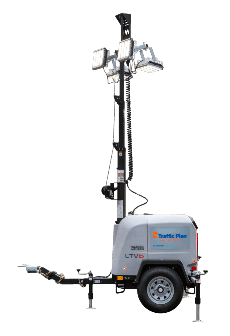 A portable mobile light tower with four mounted floodlights on an extendable pole, attached to a wheeled trailer labeled Traffic Plan. The unit has stabilizing legs and a hitch for towing.