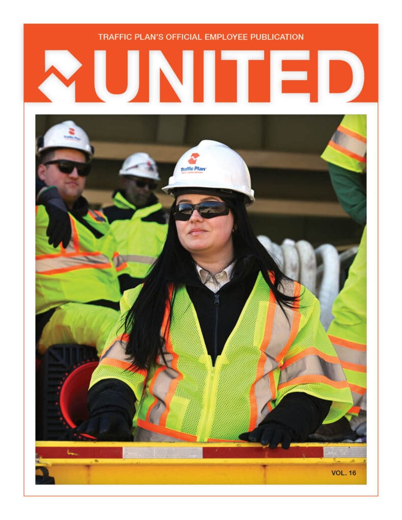 A woman wearing a hard hat, sunglasses, and a bright yellow safety jacket stands in front of other workers in similar attire on the cover of a magazine titled UNITED.