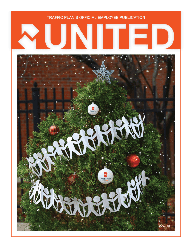 A decorated Christmas tree with paper cutouts of people, red ornaments, and branded white ornaments is shown outdoors with snow falling, featured on the cover of UNITED magazine, Volume 18.