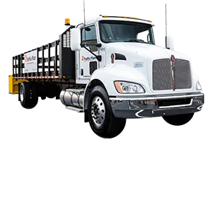 A white flatbed truck with metal side rails and a yellow barrier on the back, viewed from the front left angle. The truck has a company logo on the cab door.